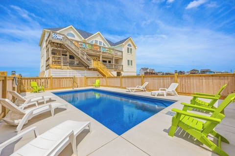 Beachfront vacation home showcasing a private swimming pool surrounded by colorful lounge chairs and expansive deck space—perfect for sun-soaked days and coastal relaxation.
