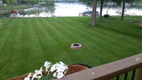 View of the yard and lakefront from the upper deck showing fire pit.
