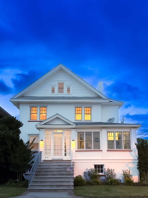 Twilight.  Front of the house showing 2nd and 3rd apartment above the porch.