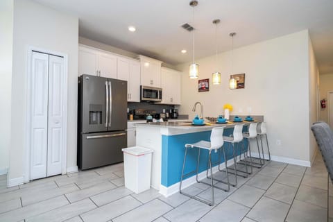 Enjoy breakfast or dinner at this modern kitchen island, featuring bright blue accents, sleek appliances, and lots of seating for your group.