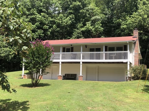 Two-story home with spacious front porch nestled in the woods right by the lake.