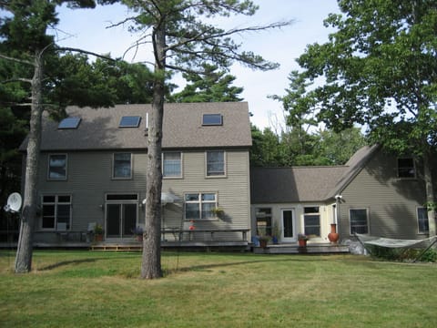 Back of the home with sits on open meadow 