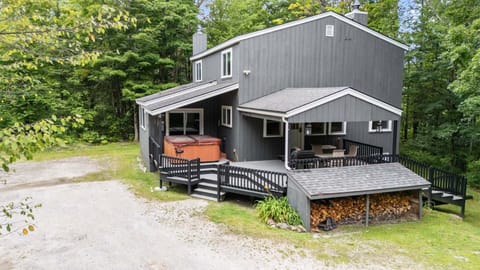 The forest-framed exterior shows off the broad decks and covered hot tub before you step inside.