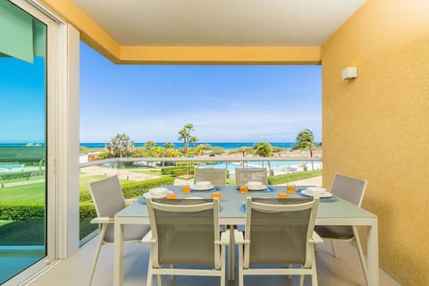 Your private terrace overlooks sparkling turquoise waters and lush gardens, with a table set for six—perfect for leisurely breakfasts with ocean breezes and tropical views.