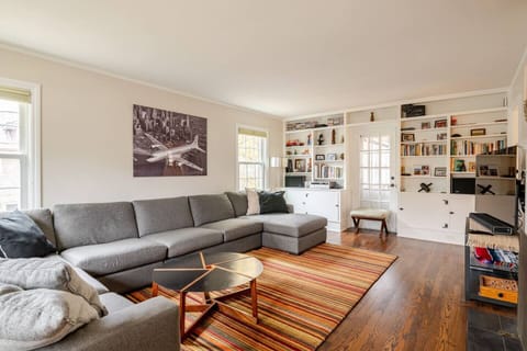 Living room with large couch, tv, games, books, and fireplace.
