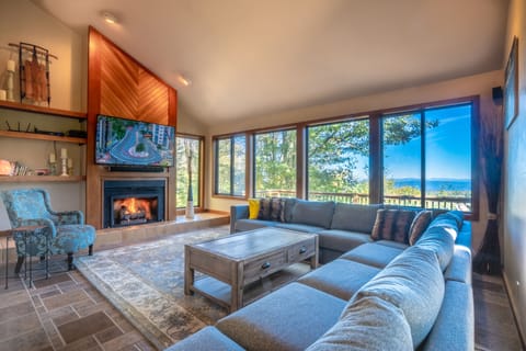 Living room with fireplace, breathtaking views & 65-inch smart television.