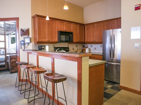 Kitchen - View from dining area into kitchen, showing the bar and bar stools.