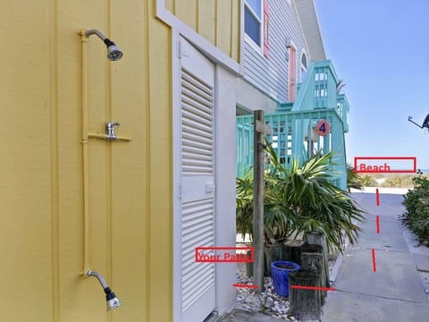 Step out from your patio and the beach is just steps away.

This charming coastal walkway leads directly toward the shoreline, with the sand and Gulf just beyond view. An outdoor shower with both overhead and handheld fixtures makes it easy to rinse 