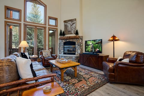 Unwind in your cozy living room where warm leather seating surrounds a crackling stone fireplace, perfect for mountain evenings together.