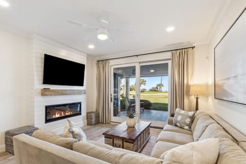 Living Area with a Tan Sectional Positioned around a Large Flat Screen Smart TV and Electric Fireplace