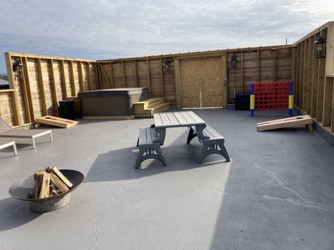 Party Patio, with hot tub, corn hole, firepit, lounge furniture, other games.