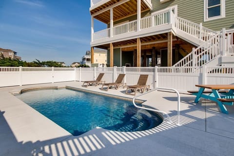 Your private oasis awaits—lounge by the sparkling pool, soak up the sun on comfortable deck chairs, and enjoy seamless access to your multi-level retreat with spacious balconies perfect for unwinding after a day at the beach.
