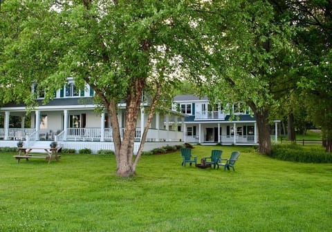 view from lake, main house with wrap around porch, mature trees, fire pit,