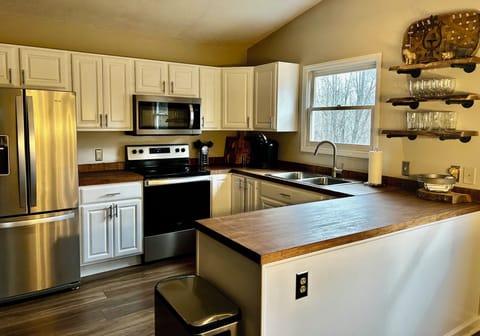 Kitchen has stainless steel appliances and butcher block countertops.