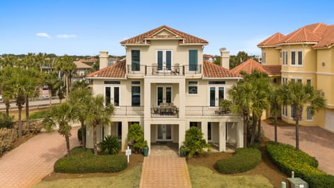 Mediterranean-style vacation home with terracotta tile roof and palm trees in an upscale coastal neighborhood.