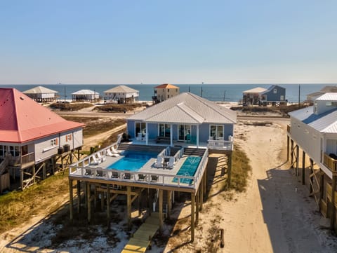 Elevated beach house community featuring coastal properties with private pools and ocean access along the sandy shoreline.