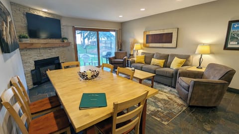 Living room with sofa bed, gas fireplace, dining table, and patio w/ gas BBQ