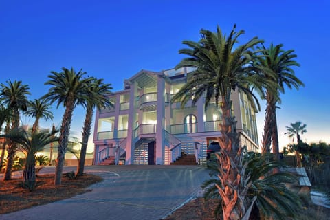 Grand exterior lit at dusk w/ palm trees and elegant architecture making a striking first impression