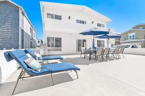This home's oversized patio includes lounge chairs, two market umbrellas, and outdoor tables and chairs
                
