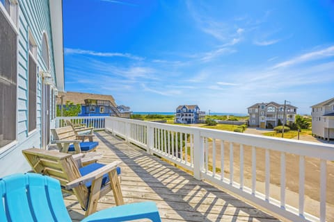 Coastal vacation rental neighborhood featuring multiple beach houses with ocean views in the background, surrounded by landscaped grounds and neighboring properties.