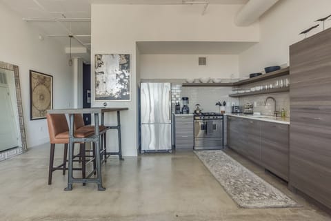 Kitchen with ample cabinetry, shelves filled with glasses and plates, and modern appliances.