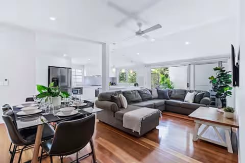 Bright open-plan living room with Samsung 50" 4K and a rollaway bed.