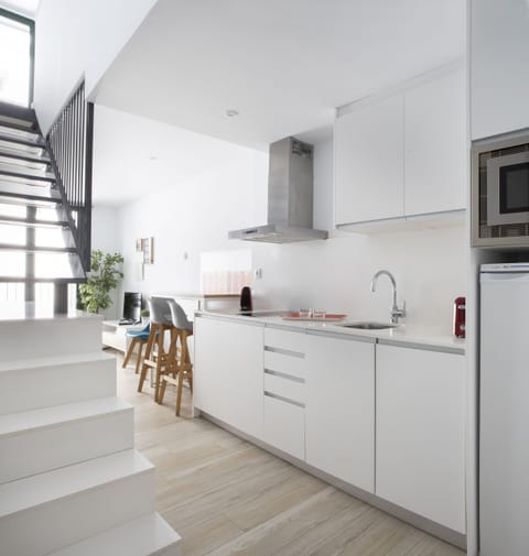 The Urban Suites Sitges holiday apartment has a kitchen equipped with a dishwasher, microwave, juicer, kettle, coffee maker and toaster. The kitchen is ceramic hob. In this photo you can see the stairs that go up to the bedroom.