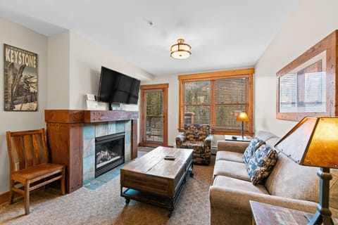 Unwind in your cozy living space featuring a warm fireplace, comfortable seating, and mountain lodge charm perfect for après-ski relaxation.
