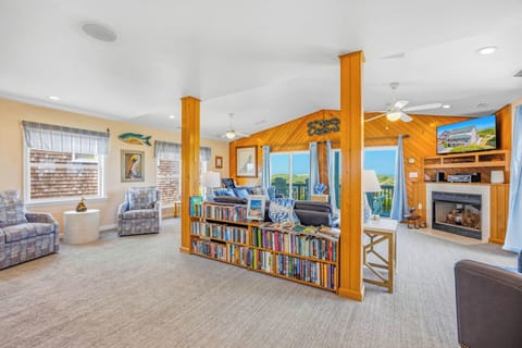 Step into your coastal retreat where natural light pours through panoramic windows, revealing stunning ocean views. Sink into plush seating, browse the extensive library, or warm up by the fireplace as you unwind in this inviting, thoughtfully designed liv