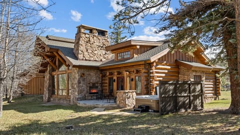 Rustic log home with outdoor stone fireplace and porch seating