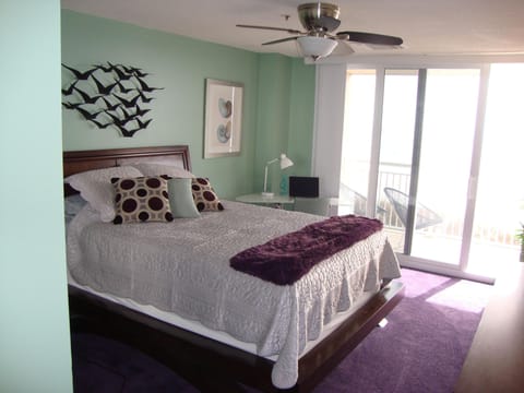 queen primary bedroom with ocean front balcony, modern desk and chair