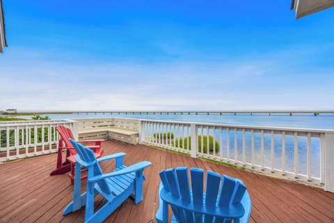 Settle into colorful Adirondack chairs on your private deck and take in sweeping water views, with a long bridge stretching across the horizon and soft grasses swaying below.