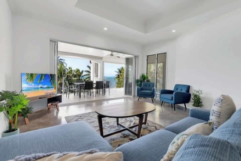 The living area offers a comfortable lounge and wicker chairs fronting a central TV.
