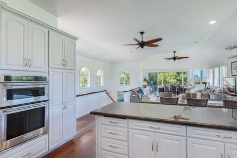 Gourmet kitchen with white cabinetry and wood floors, blending modern style with island charm and functionality.