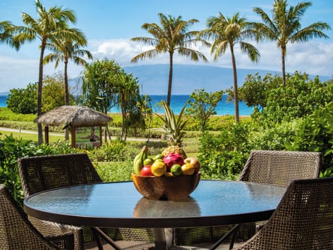 Enjoy breakfast on a lush tropical patio with views of the ocean and palm trees, a perfect start to your day in paradise.