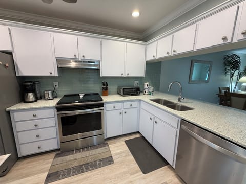 Your fully equipped kitchen features modern appliances, granite counters, and coastal charm with turquoise subway tiles.