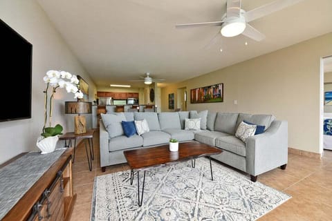 Living room with sectional sofa, coffee table, and kitchen access.