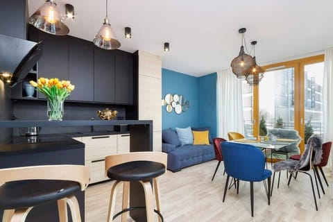 A stylish room with a black and blue color scheme, featuring a dark dining table, blue curtains, and a cozy seating area with decorative lighting.