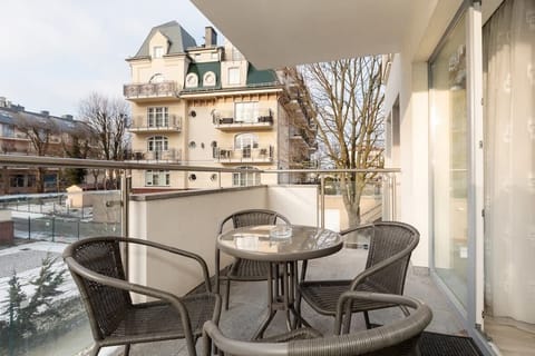 A balcony with a small table and chairs, providing a cozy outdoor space overlooking the surroundings, perfect for enjoying fresh air.