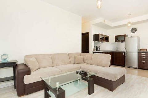 The same living room area, showing a different angle of the beige sectional sofa, glass coffee table, and minimal decor.