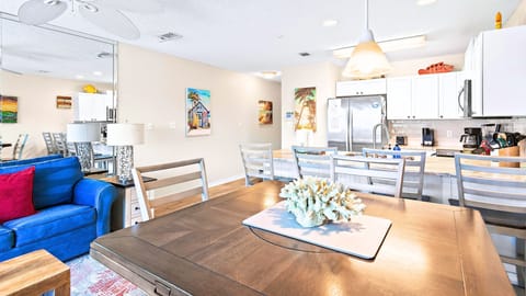 A bright living room with a bold blue sofa and beachy art.