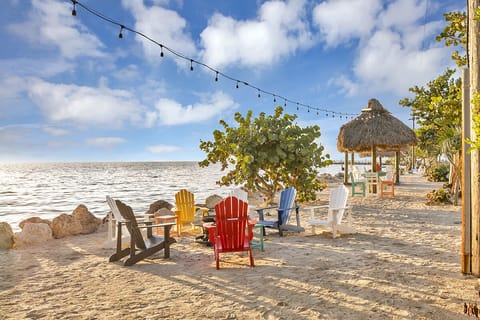 Beach with fire pits, charcoal grills, and cafe lights for night time.