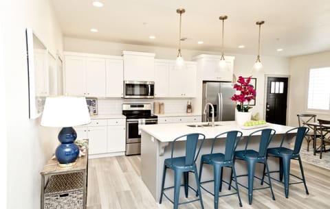 Bright, modern kitchen with large island, bar seating, and stainless appliances.