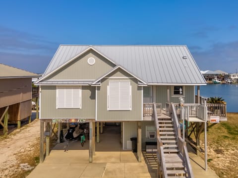Charming waterfront cottage on stilts with bay views and covered parking, featuring coastal architecture and outdoor living spaces.