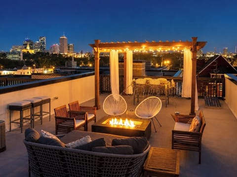 Rooftop fire pit lounge with dining area and stunning city skyline views
