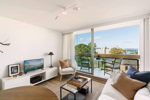 Our lovely, comfy living space with balcony + view of our charming neighborhood and the ocean!