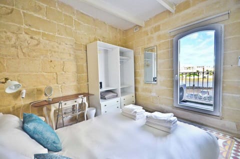 Bedroom area is equipped with a large king-size bed and offers balcony views of the Grand Harbour.