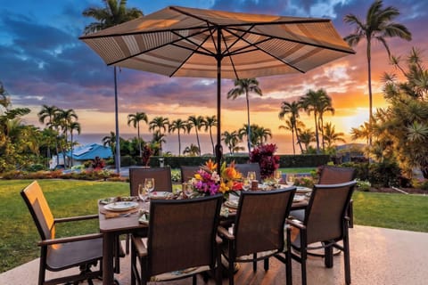 An elegant outdoor dining setup on a tropical property at sunset, surrounded by lush palm trees and landscaped gardens, offering a scenic backdrop for al fresco meals during your stay.
