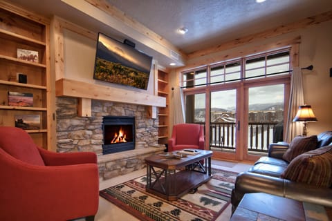 Cozy up by your crackling stone fireplace in this mountain living space, where rustic wood beams and warm leather seating create the perfect retreat after your adventures.