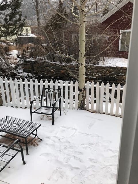 The stream is between the white picket fence and the rock wall —a lovely sound!